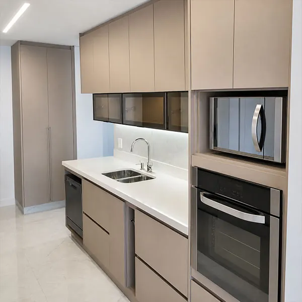 Cozinha planejada em tom fendi com forno e micro-ondas embutidos e bancada em quartzo